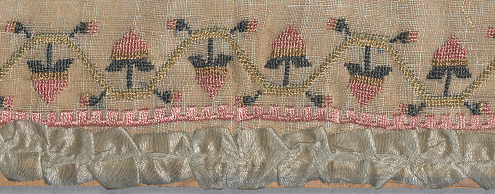 Detail of bottom edge of sampler featuring a flora border and ribbon trim.