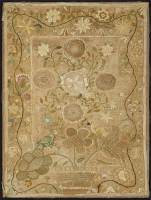Whitework sampler on original mount. Details include central flowers in whitework growing from a whitework pot, embroidered flowers around the border, and two embroidered birds.